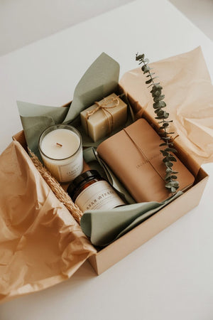Wellness & Self-Care gift box featuring a candle, notebook, soap, and greenery for relaxation and joy.
