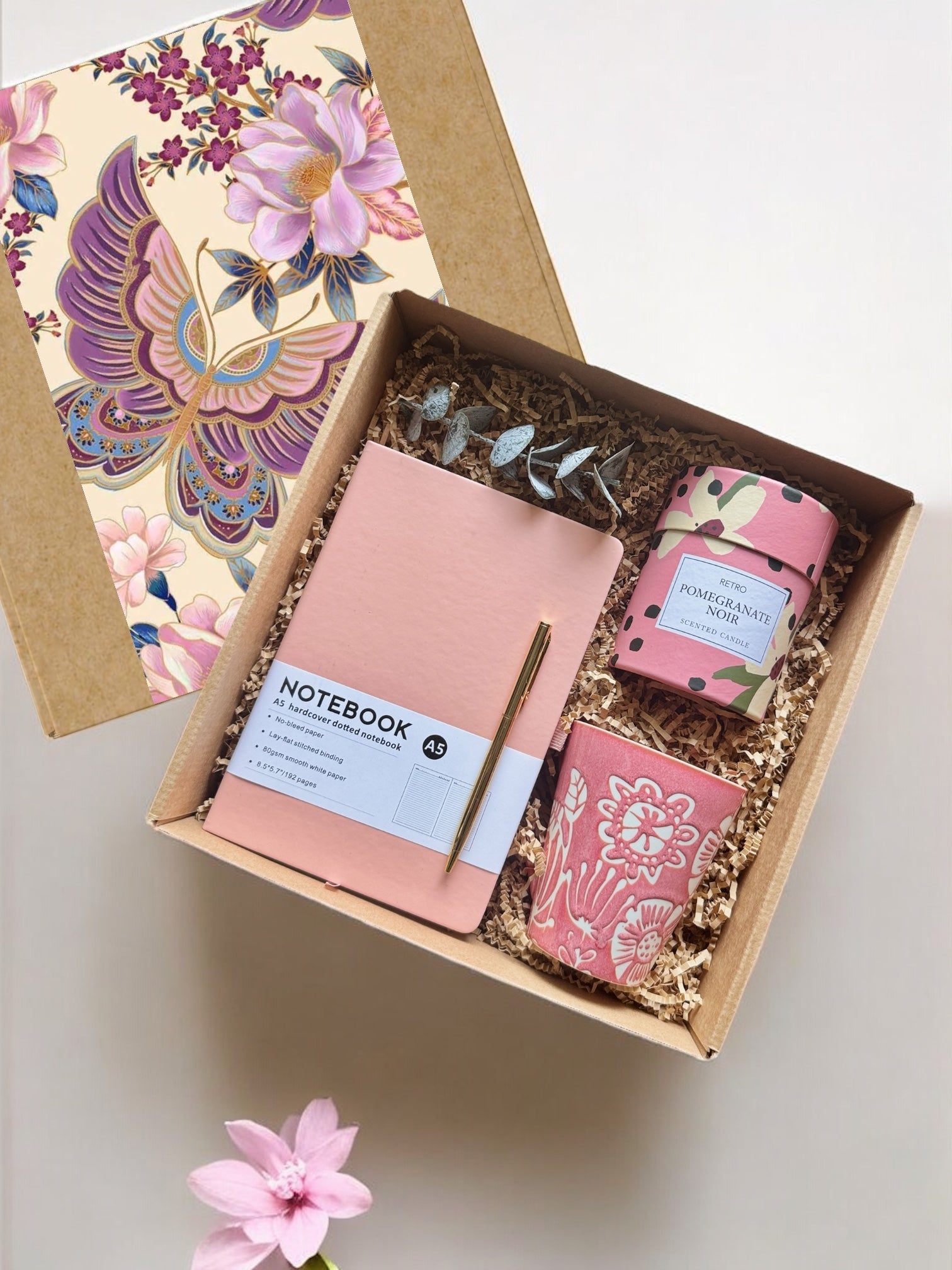Gift set with notebook, candle, and card in a decorative box on a light background
