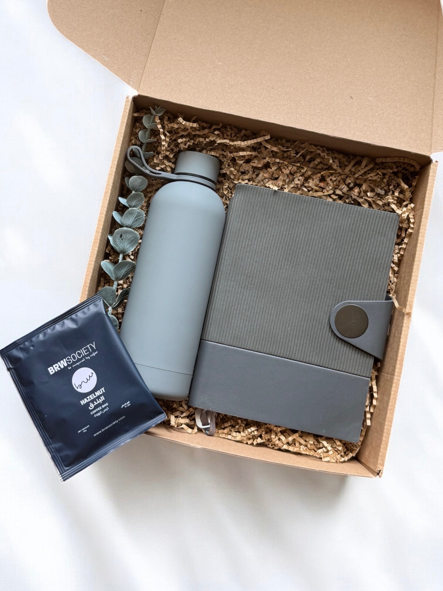 Box containing a water bottle, notebook, and instant coffee