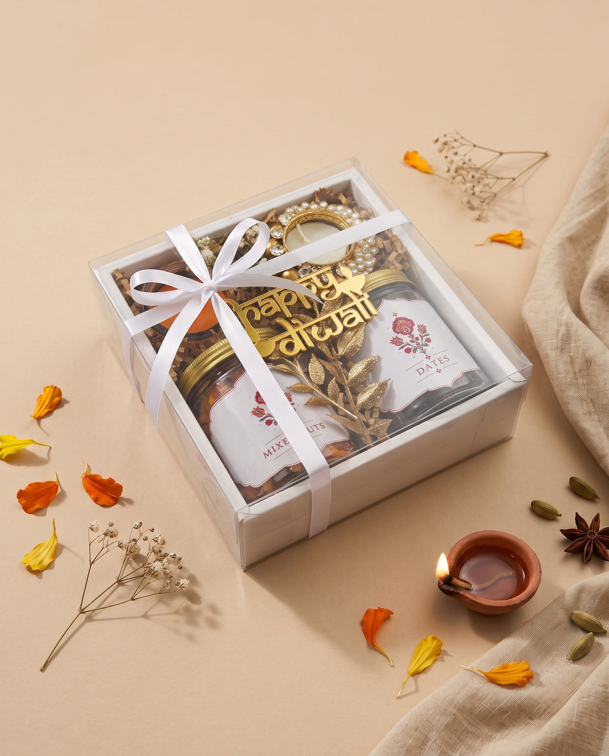 Mini Diwali Box featuring jars of mixed nuts and dates, a diya, and decorative elements for Diwali celebration.