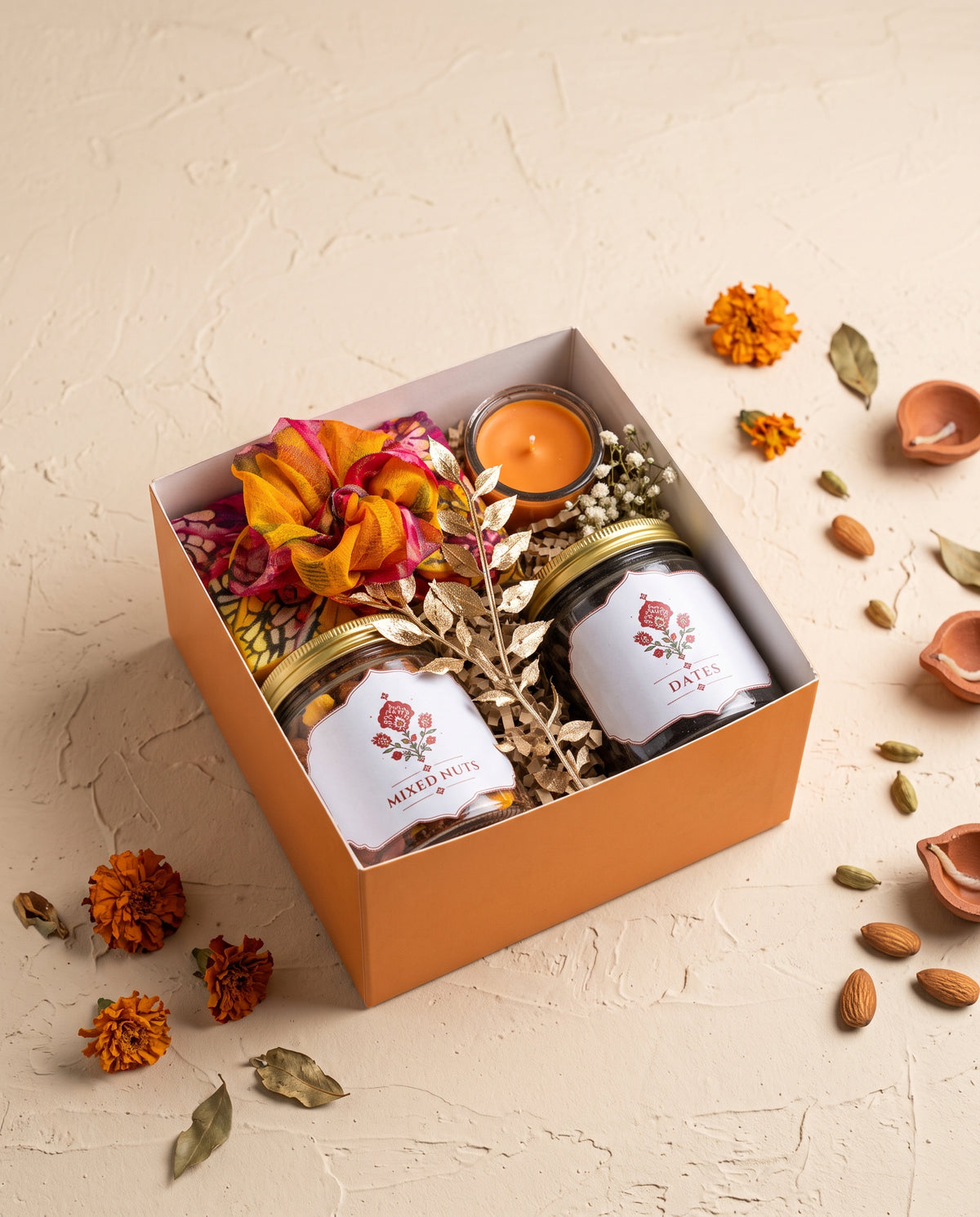 Saffron Glow Diwali Box featuring mixed nuts, dates, and a candle in an elegant keepsake gift box.