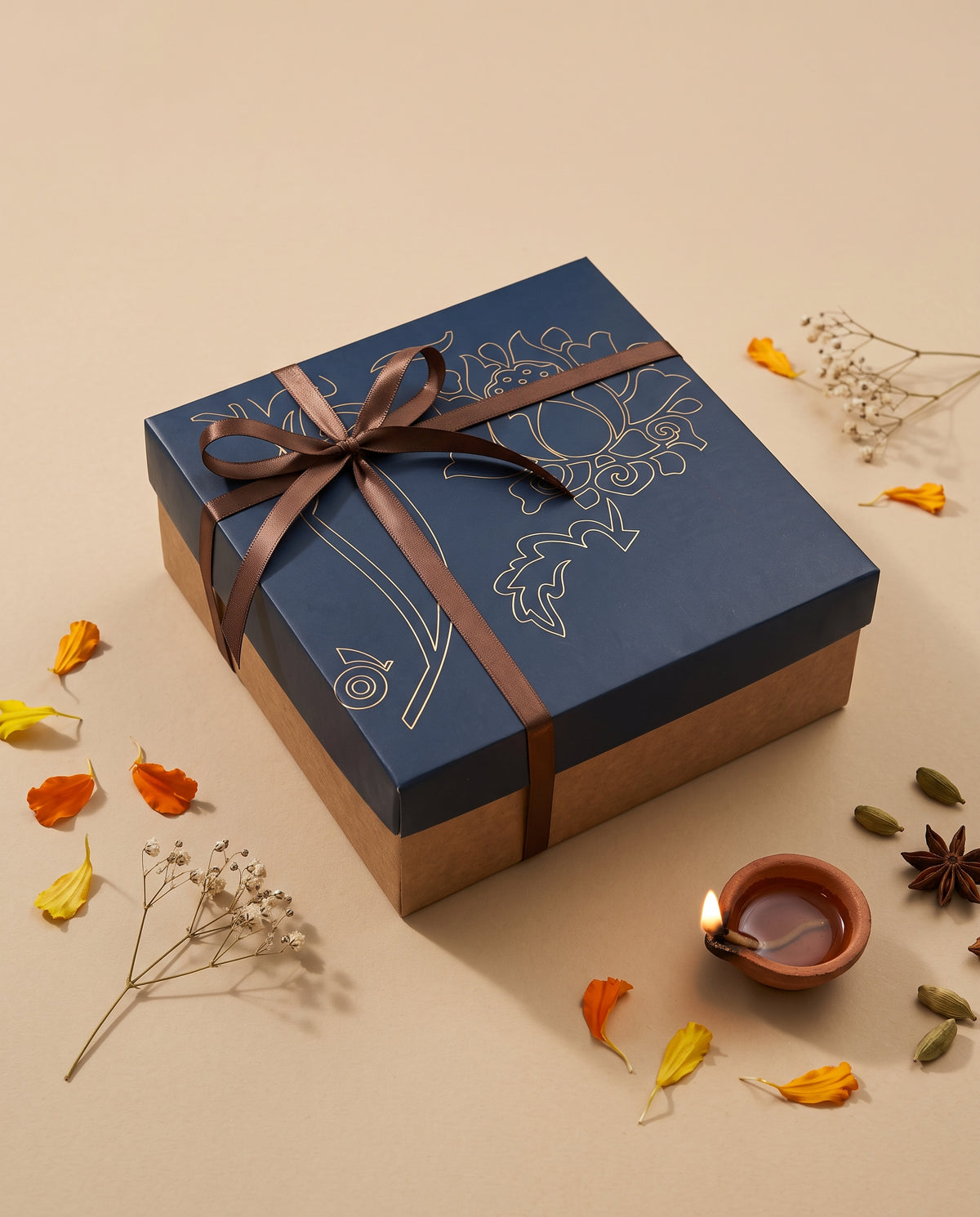 Blue Lotus Diwali Box elegantly wrapped with a ribbon, surrounded by festive decorations and a diya.