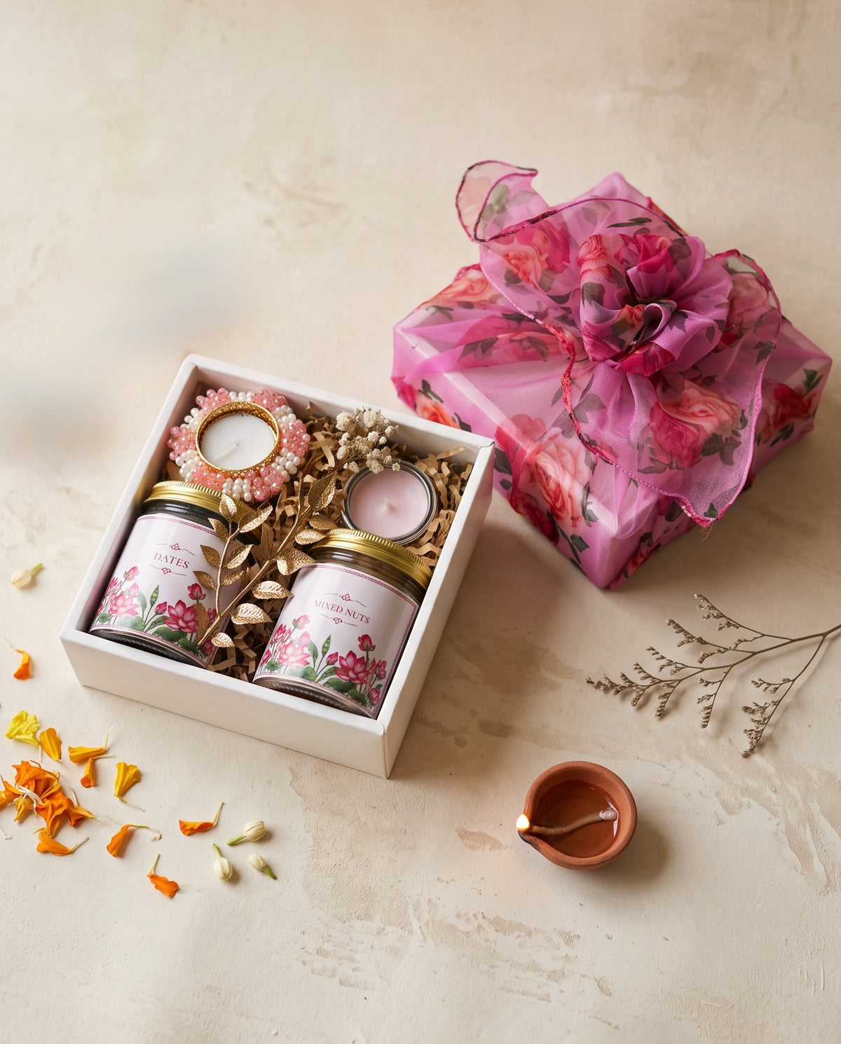 Rose Diwali Box with jars of dates and mixed nuts, a mini pink candle, and a floral gift wrapping.