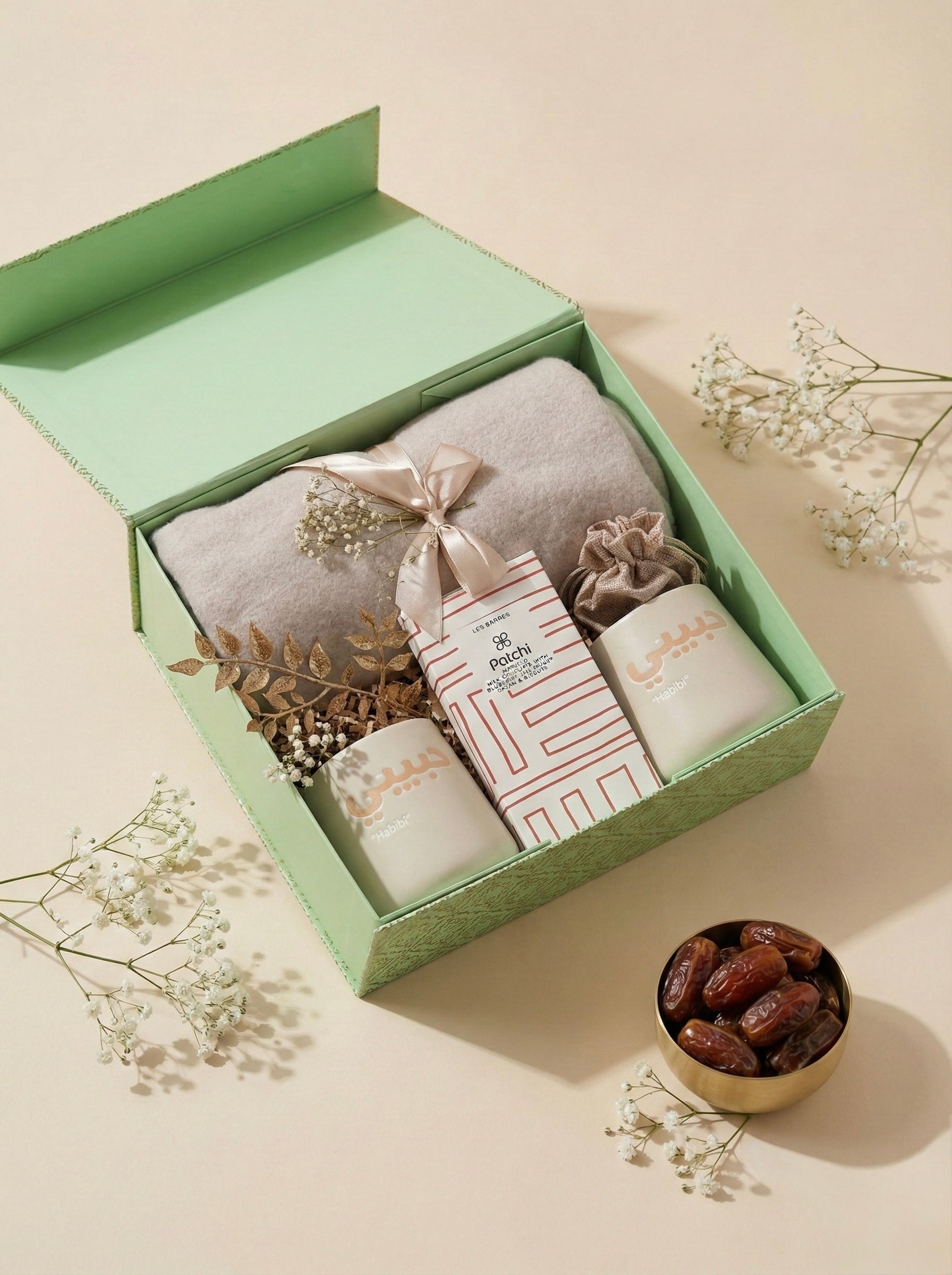Modern minimalist gift box featuring mugs, a blanket, and decorative elements.