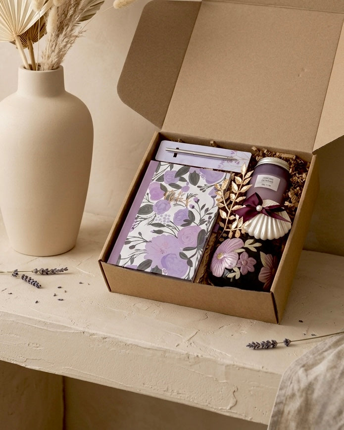 Lavender gift box for women containing a floral notebook, chocolate, ceramic mug, and candle in an eco-friendly kraft box.