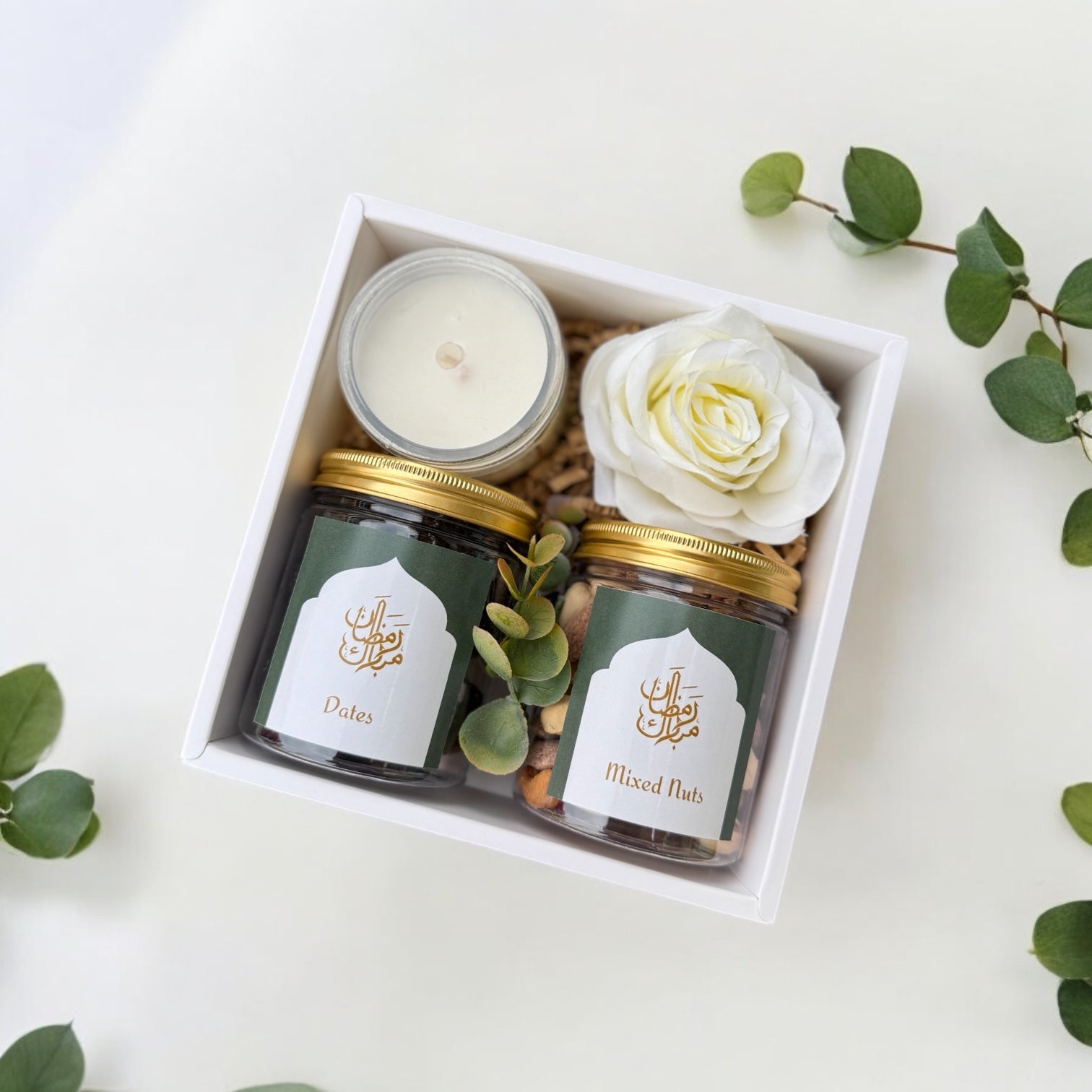 Minimal gift set featuring a scented candle, jar of dates, and jar of mixed nuts in an elegant presentation.