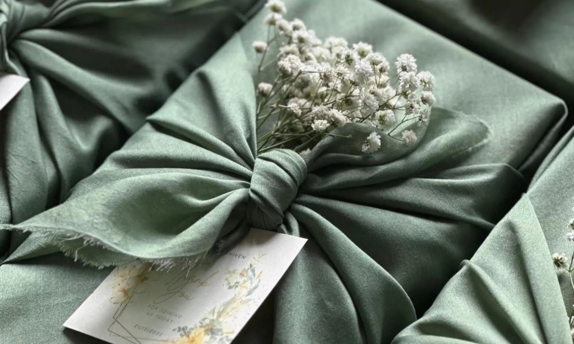 Luxury gift hamper wrapped in green satin fabric with white flowers UAE