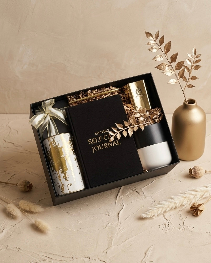 Luxury gift box UAE featuring a self-care journal, gold candle, ceramic mug, and decorative elements.