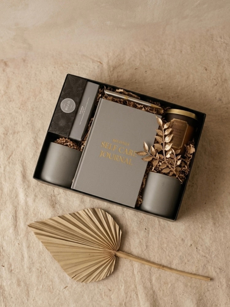 The Serene Sip Gift Box is a wellness gift box for her, featuring a self-care journal and elegant matte grey mugs.