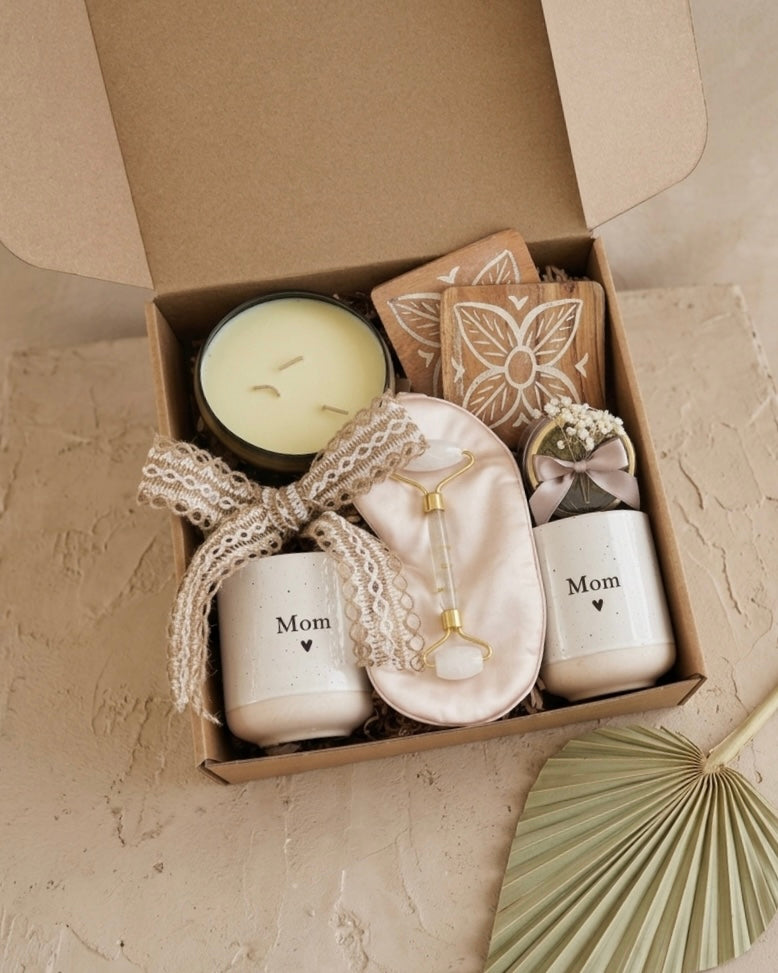 Luxury gift set for mom featuring a candle, ceramic mugs, herbal tea, and a satin sleep mask in eco-friendly packaging.
